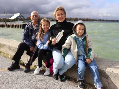 Makenzie Van Eyk (second from right) holds the message in a bottle that she wrote 26 years ago. Roland St. Pierre (far left) was her teacher at the time. Her daughter Scarlet (second from left) and son Huxley (far right) are enrolled in the same school she attended.