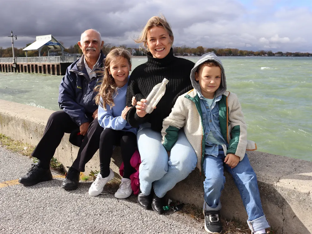 A man, two children and a woman sitting next to a body of water