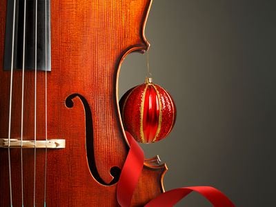 A portion of a violin is shown accented with red ribbon and an ornament