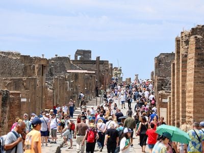 A crowd of tourists gathers on the main street at Pompeii.