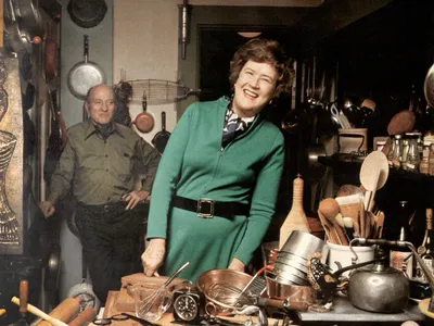 Julia Child in her kitchen with husband Paul behind her