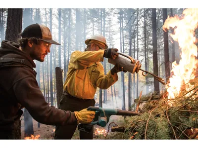 Saylor Flett, left, fans flames ignited by Jeff Greef. Air quality, weather and even bird migration affect when it’s safe to conduct a burn.