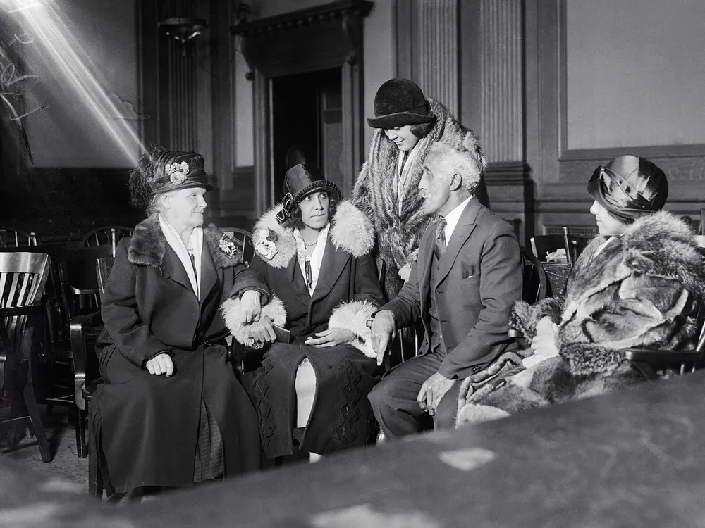 Alice Beatrice Rhinelander, née Jones (seated at center), looks at her father, George Jones, as they await the verdict in the Rhinelander v. Rhinelander ​​​​​​​case.