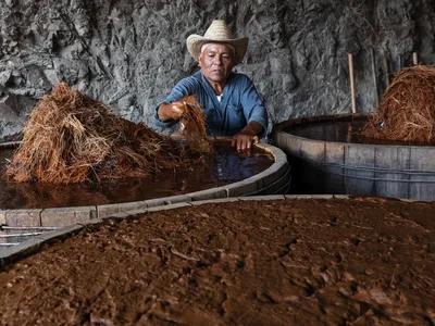 Jos&eacute; Santiago of Palenque Don Lencho, in San Pablo Guil&aacute; village, with wooden vats of fermenting agave prior to distillation